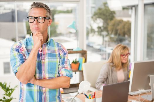 Thoughtful casual designer in front of his working colleague in the office