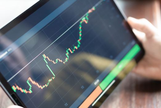 Closeup hand holding digital tablet computer with graph of Binary option for trading platform, setective focus