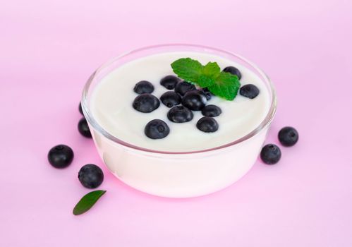 Close up yogurt with fresh blueberries  fruit in glass bowl  on pink backgroun