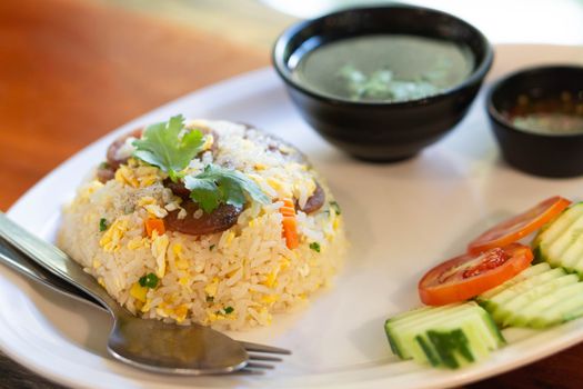 Closeup fired rice with sausage and vegetable in plate on wood table