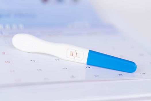 Closeup pregnancy test on calendar background, health care concept, selective focus