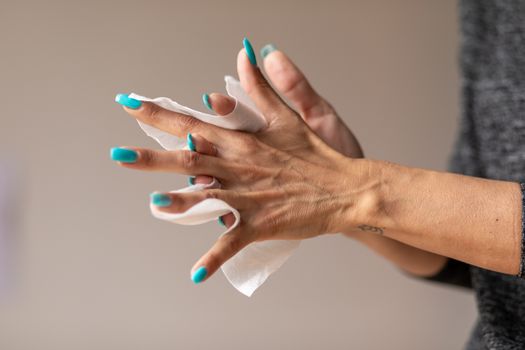 Old woman gently cleaning hands with wet wipes, white