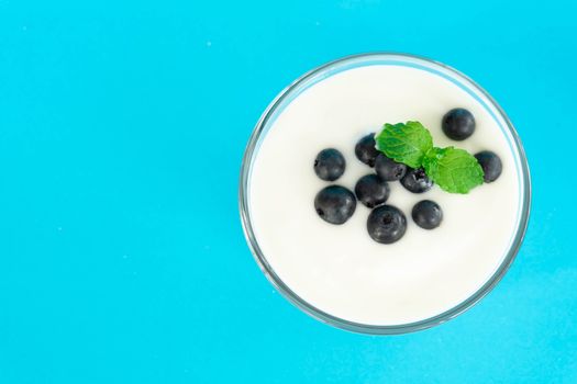 Close up yogurt with fresh blueberries  fruit in glass bowl  on blue background