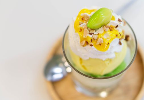 close up glass of mango ice cream with wipped on white background, copy space