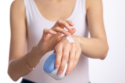 Young woman applying hand cream to protect and care skin, close up.