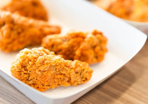 Close up fried chicken legs in white tray on wood table