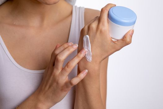 Young woman applying hand cream to protect and care skin, close up.