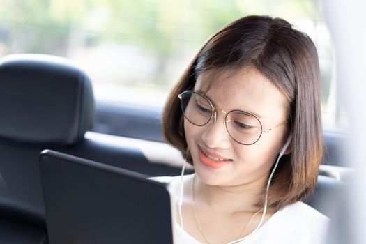 Closeup asian woman using digital tablet in a car with happy face
