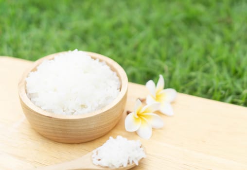 Close up white rice in wooden bowl with green nature background, healthy food, selective focus