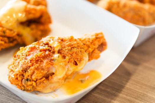 Close up fried chicken legs in white tray on wood table