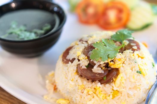 Closeup fired rice with sausage and vegetable in plate on wood table