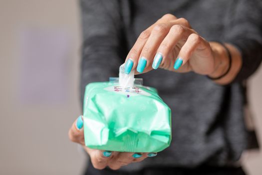 Old woman hand with turquoise nails taking the wet wipe to clean skin or surface stock photo