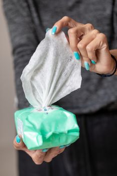 Old woman hand with turquoise nails taking the wet wipe to clean skin or surface stock photo