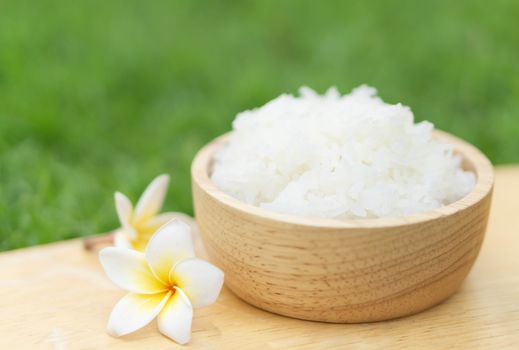 Close up white rice in wooden bowl with green nature background, healthy food, selective focus