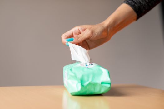 Old woman hand with turquoise nails taking the wet wipe to clean skin or surface stock photo