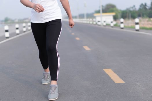 Close up woman legs running on the road at morning, selective focus