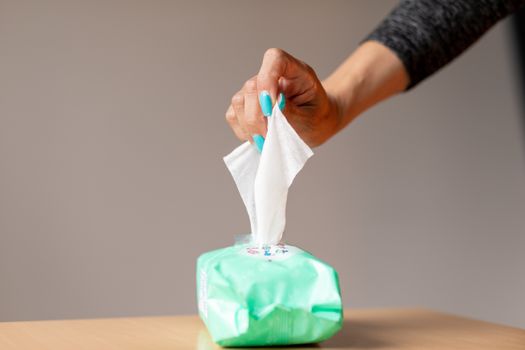 Old woman hand with turquoise nails taking the wet wipe to clean skin or surface stock photo