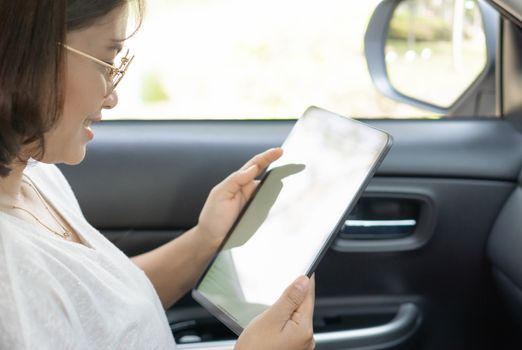 Closeup asian woman using digital tablet in a car with happy face