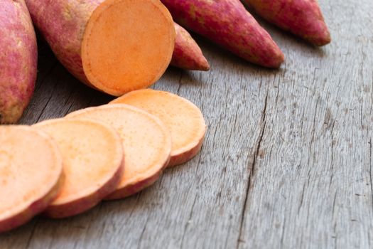 Sweet potato with slices on wooden background, raw food 