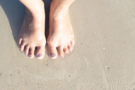 Closeup woman feet standing on sea sand with relaxing time feeling in the holiday