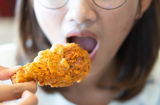 Close up woman eating fried chicken legs, selective focus