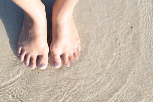 Closeup woman feet standing on sea sand with relaxing time feeling in the holiday