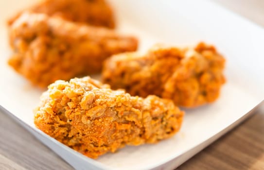 Close up fried chicken legs in white tray on wood table 