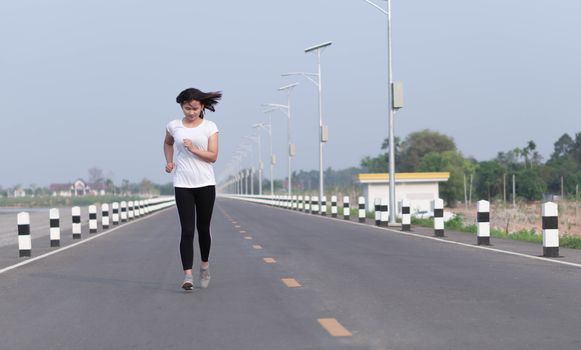 Close up asian woman running on the road at morning, selective focus