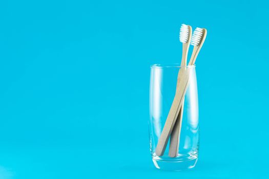 Wooden toothbrush in glass with blue background, selective focus