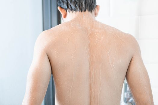 Closeup handsome asian man taking a shower in the bathroom, selective focus