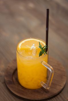 Glass of fresh orange juice with slice on wooden table