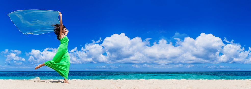 Female model in long green dress run on beach waving white fabric, vacation, freedom concept