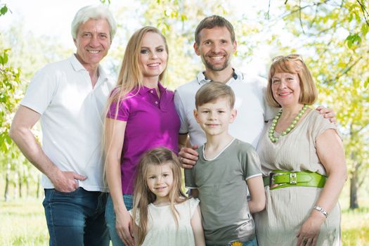 Multigeneration family portrait outdoors. Happy parents with two children and grandparents in summer park