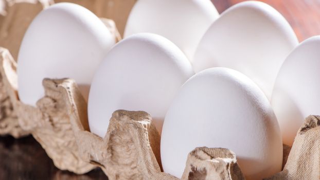 Chicken eggs in the morning sun. Raw eggs in a tray close-up on the kitchen table.