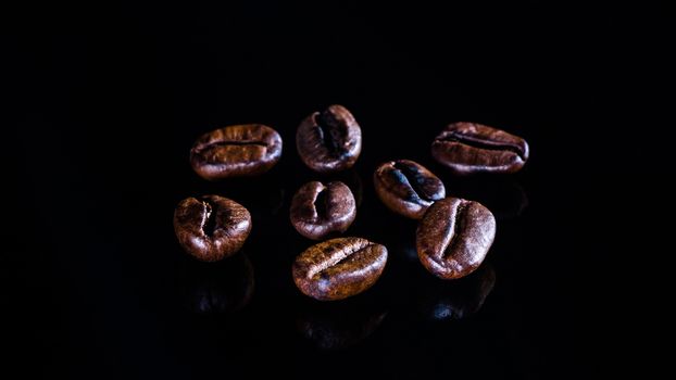 Coffee beans on a black mirror background close-up.