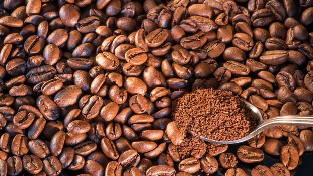 Coffee beans close-up with a spoon of ground coffee on a mirror background.