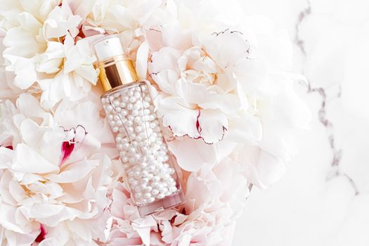 Luxurious cosmetic bottle as antiaging skincare product on background of flowers, blank label packaging for body care branding design