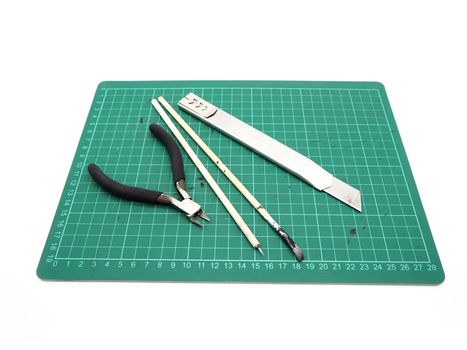 Tools with green cutting mat for model kit isolated on white background.