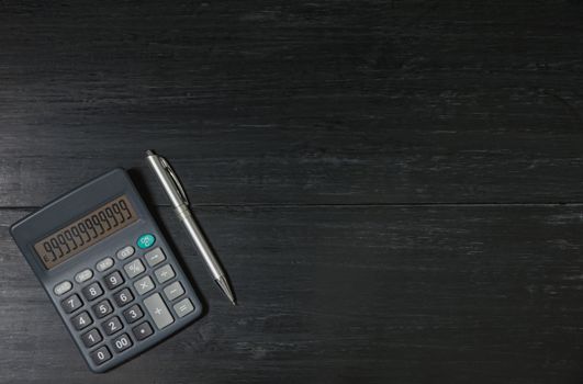 A calculator and pen on wooden background with copy space for insert text.