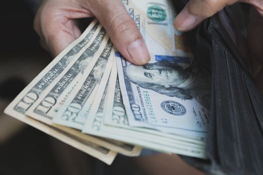 Hand holding a banknote in wallet for financial, accounting and saving money concept.
