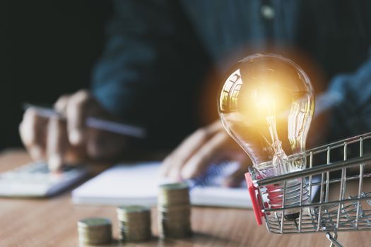 Stack of coin and light bulb in the shopping cart for accounting and business concept.