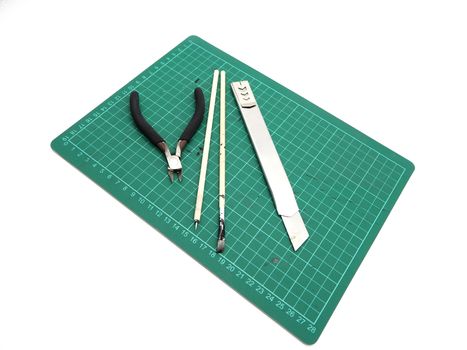 Tools with green cutting mat for model kit isolated on white background.