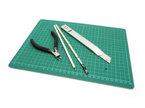 Tools with green cutting mat for model kit isolated on white background.