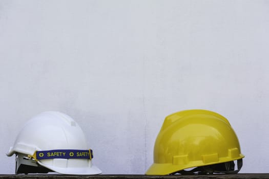 Construction Helmet, yellow and white safety helmet on wooden table.