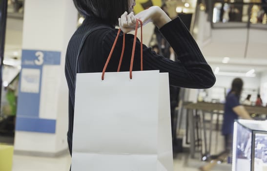 Young Asian woman holding shopping bag in shopping mall. Shopping concept.