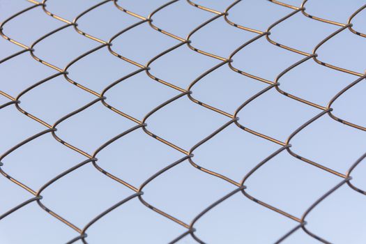 Old and rusty iron net wrapped on blue sky background.