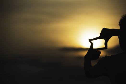 Hands making frame with sunset. Close up of woman hands making frame gesture.