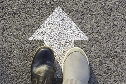 Top view of man wearing black and white shoes choosing a way marked with white arrows. Chooses the right path concept.