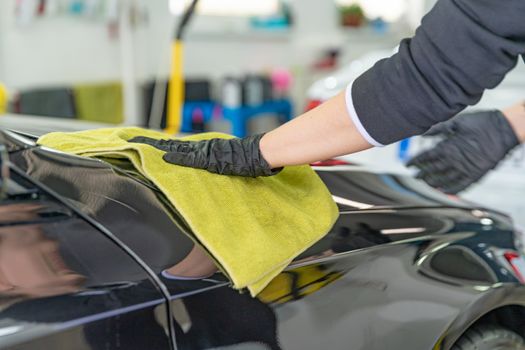 polishing the body of luxury cars with the help of a microfiber cloth for a perfect shine.