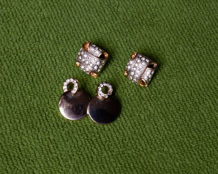 Gold jewelry, earrings lie on a green background